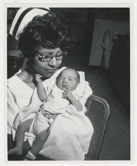 Nurse holds up a newborn infant