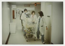 Doctors roll infant incubator down the hallway