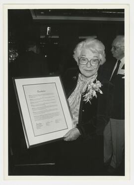 Dr. Desmond hold a framed award plaque