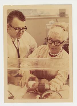 Dr. Paul Gillette and Dr. Murdina Desmond examine an infant in an incubator